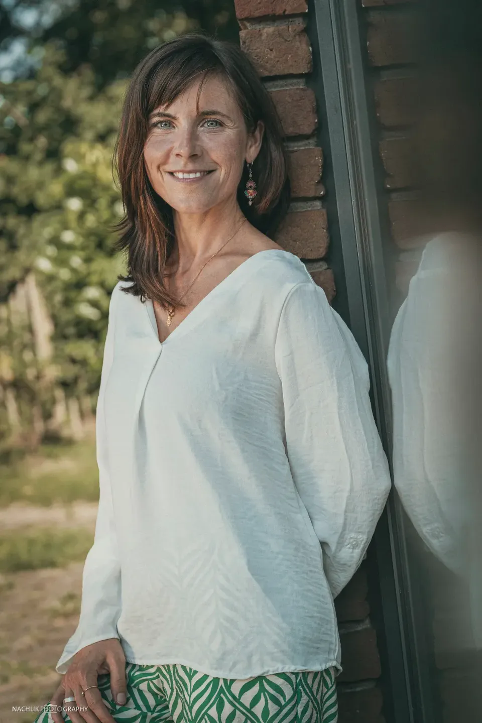 Diana Ernst, lächelnd an eine Backsteinwand gelehnt